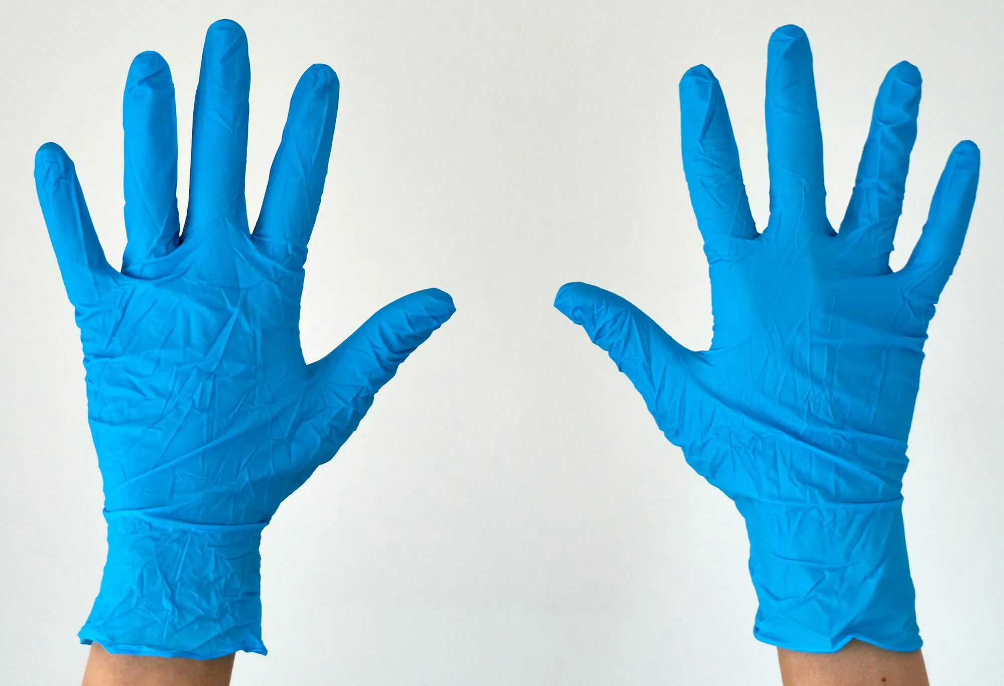 Two hands in blue disposable gloves