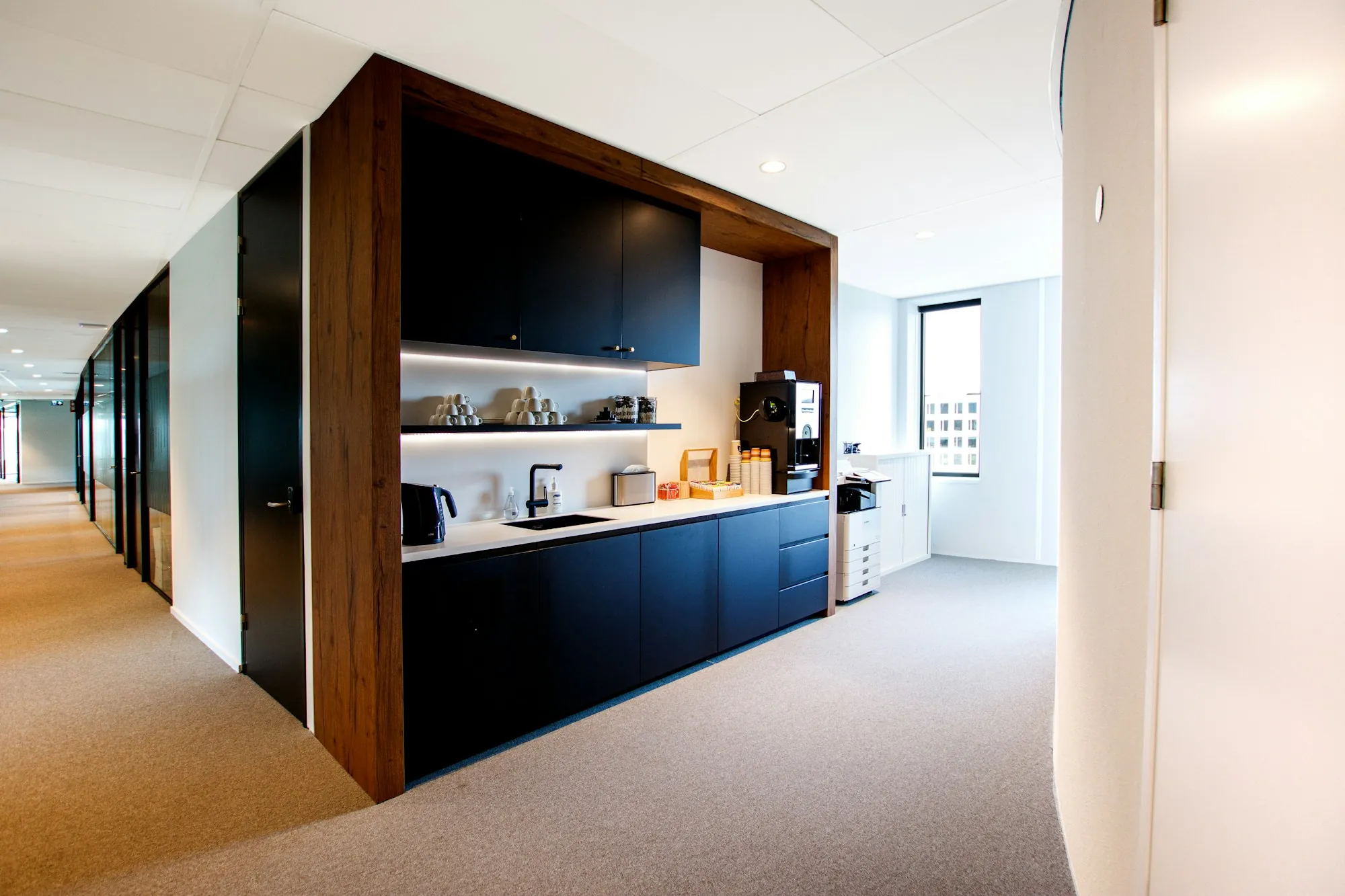 Office kitchen nook off a carpeted corridor